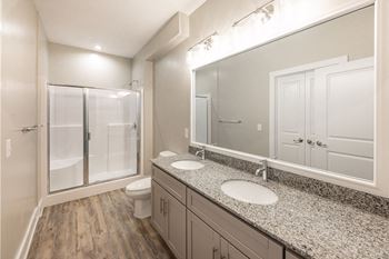 A bathroom with a sink, mirror, and shower.